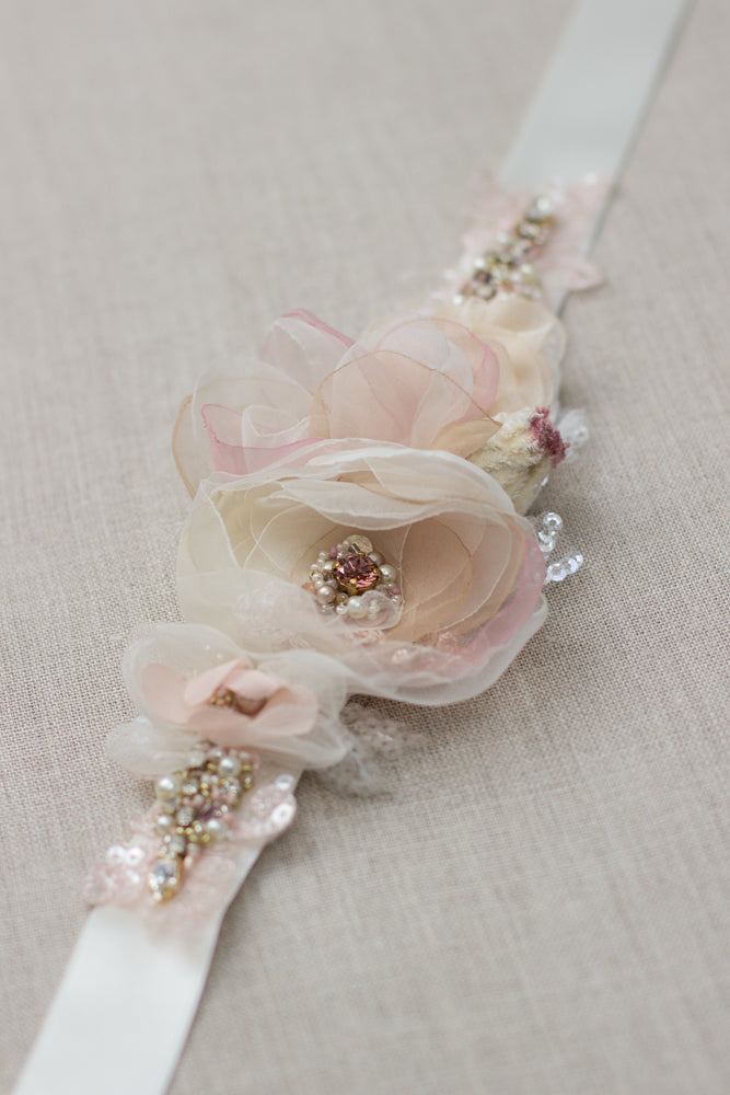 A unique handmade wedding dress belt sash features champagne, blush pink, dusty rose, beige accents. Floral design bridal sash belt is perfect for rustic, spring, or summer weddings. An online boutique with one-of-a-kind wedding accessories.