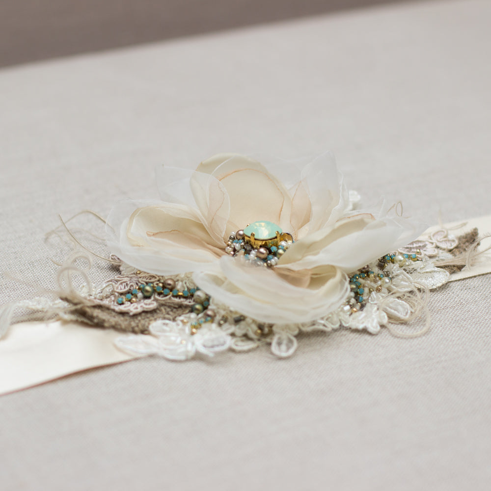 A unique handmade wedding dress belt sash features champagne flower, gold, greenish crystals, burlap accents. Floral design bridal sash belt is perfect for rustic, spring, or summer weddings. An online boutique with one-of-a-kind wedding accessories.