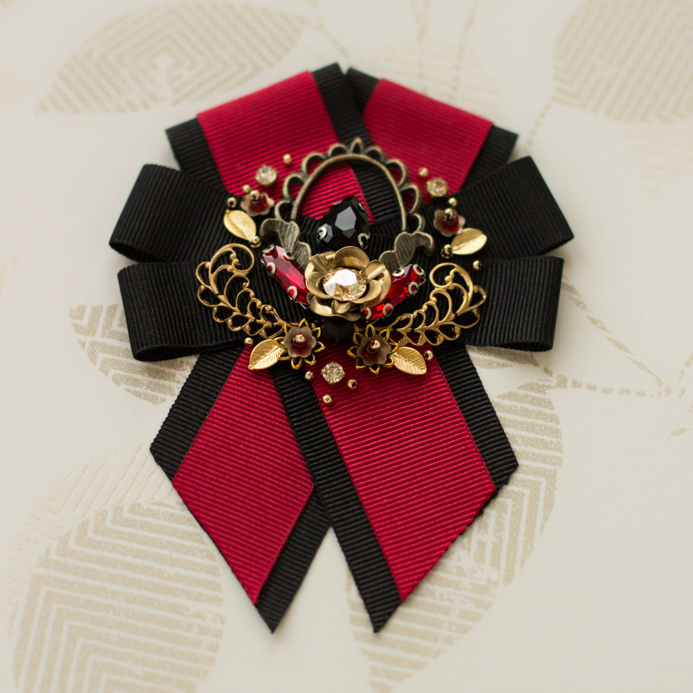 Find the perfect handmade wreath brooch with red & black ribbon, gold floral detailing and crystals. Browse our selection of unique accessories - great for gift ideas.