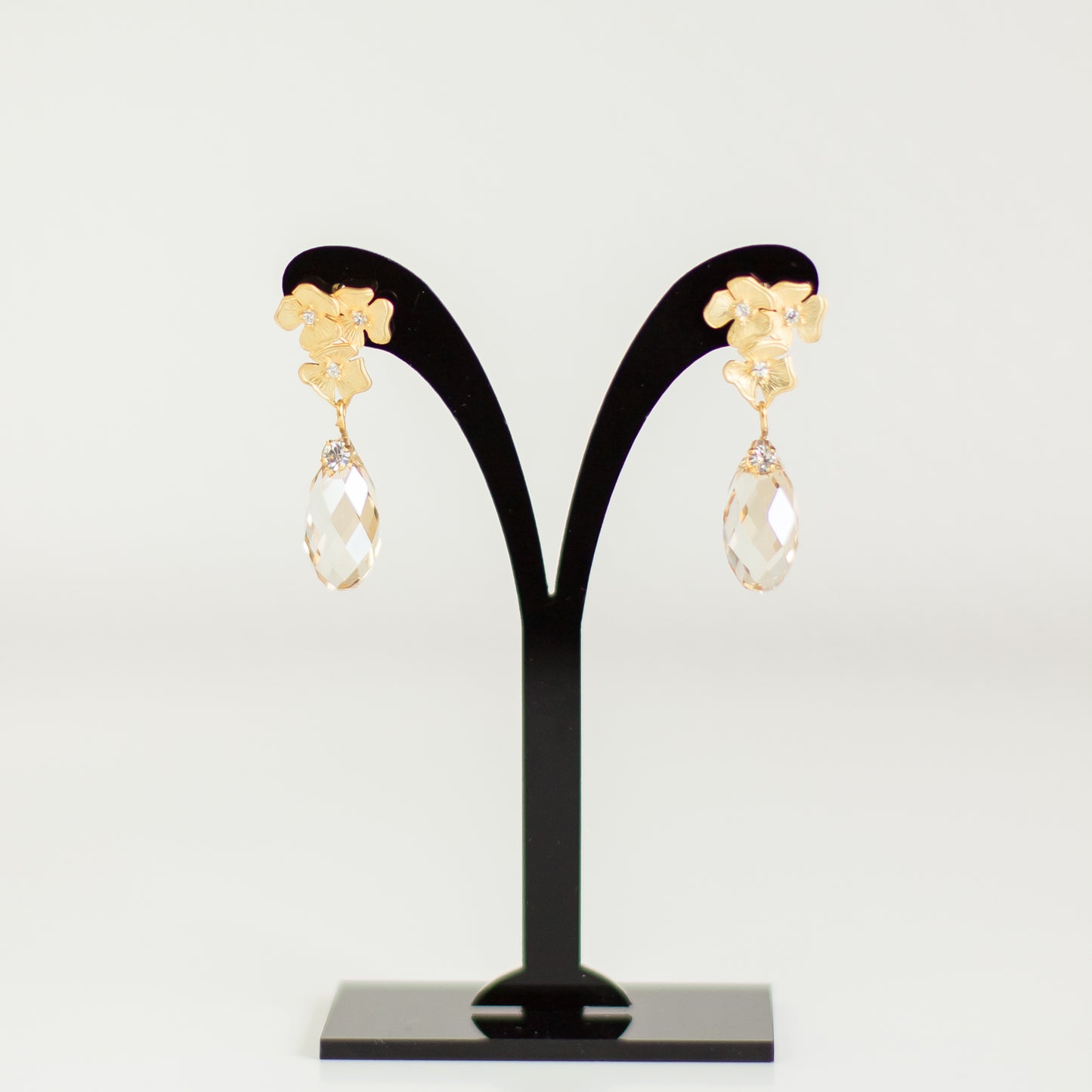 Discover these elegant crystal earrings featuring delicate floral studs and drop-shaped Swarovski golden shadow crystals, perfect for any occasion.