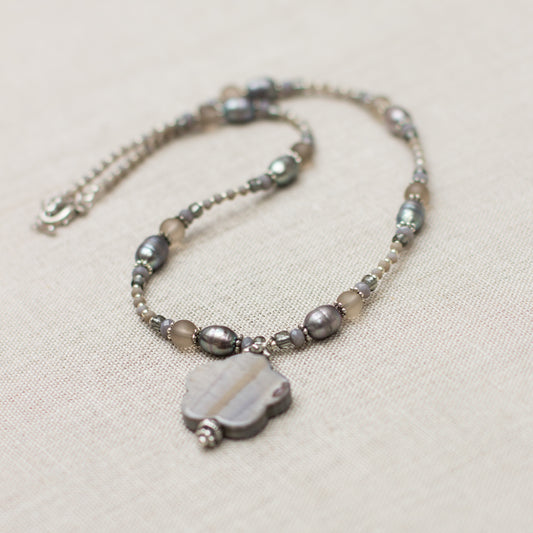 Shop a handmade gray necklace featuring freshwater pearls, glass, and a mother-of-pearl pendant. This beautiful natural stone necklace is perfect as a gift.