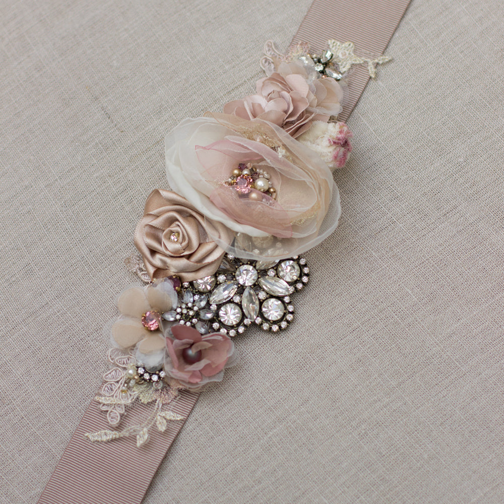 Shop online for a handmade dusty rose, blush, pale pink, beige, and tan wedding dress sash belt. Crystal bridal belt sash, featuring a floral design. Unique handmade wedding accessories for a romantic rustic, spring or summer wedding. 